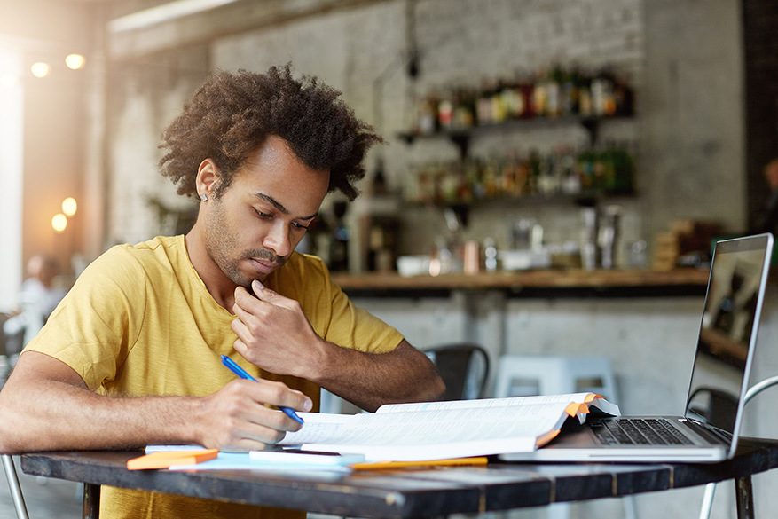 Solemn dark-skinned African American student at his workplace looking in his copy book writing notes reparing for final exams at university. Concentrated handsome guy working in cafe during break Humanitarian Aid delivery truck image